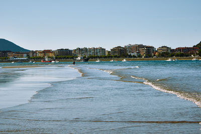Scenic view of beach and buildings against clear sky