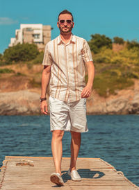 Full length of man wearing sunglasses standing against sea