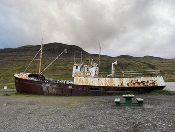 Abandoned boat on land against sky