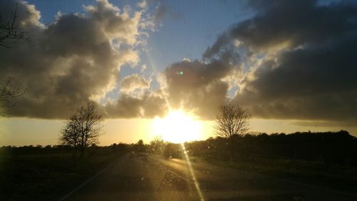 Road amidst silhouette landscape against sky during sunset