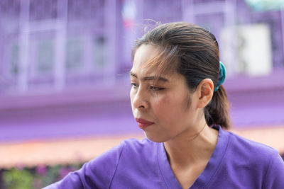 Low angle view of mid adult woman looking down while standing against building in city