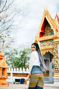 Full length of young woman standing against temple