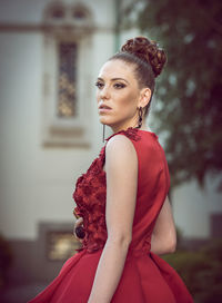 Young woman wearing red dress looking away at event