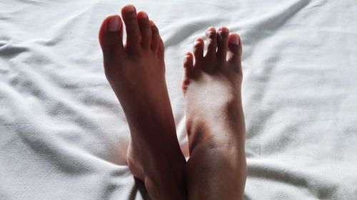 Low section of woman resting on bed