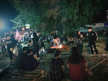 People standing by tree at night