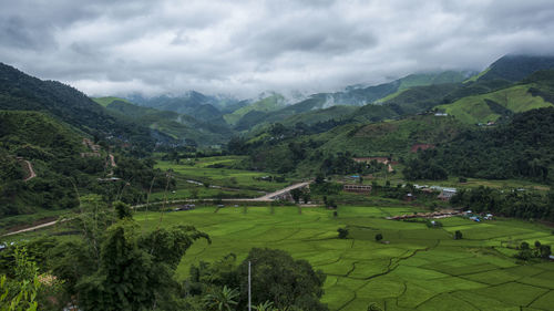 Scenic view of green landscape and mountains against sky