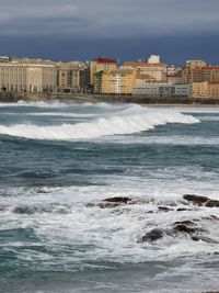 Sea by buildings against sky in city