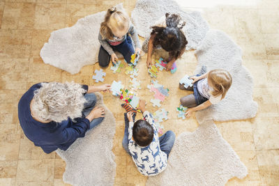 High angle view of teacher and children playing jigsaw puzzle