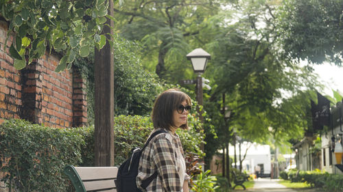 Side view of woman standing against trees