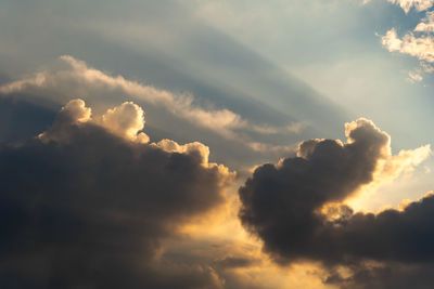 Low angle view of sunlight streaming through clouds