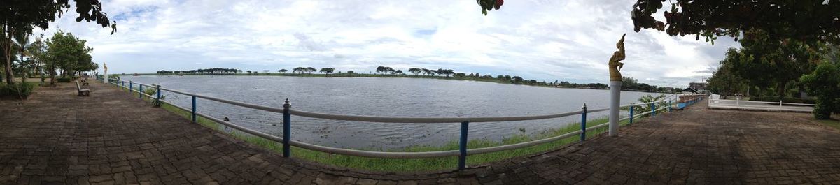 Panoramic view of footpath by river against sky
