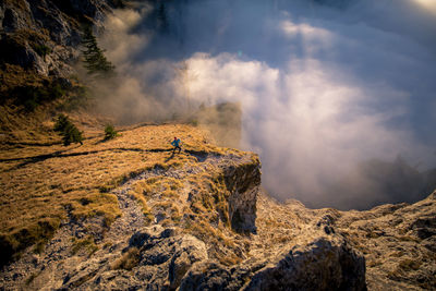 Scenic view of smoke by mountains with woman running on rocks