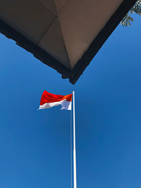 Low angle view of flags against clear blue sky