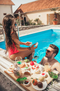 Young beautiful couple eating cookies by the pool