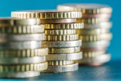 Close-up of stacked coins on table against blue background