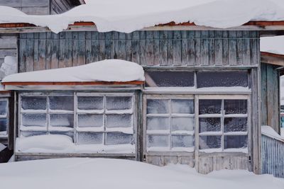 Snow covered house against buildings