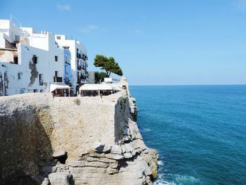 Buildings by sea against clear sky