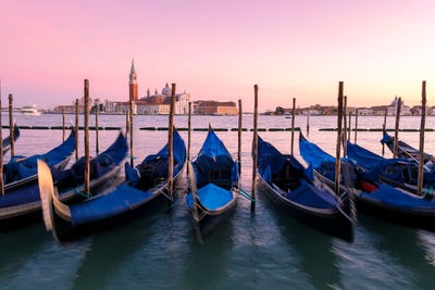 Boats moored in canal at sunset