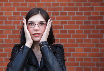 Portrait of woman against brick wall