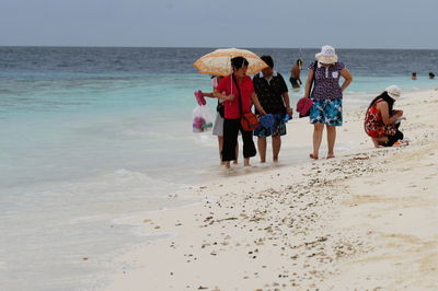 Rear view of women on beach against sky