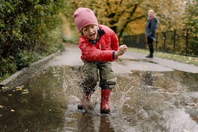 Playful boy splashing water in puddle on road