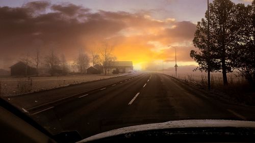 Empty road against cloudy sky at sunset