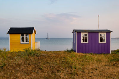 House on beach by buildings against sky