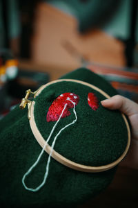 Close-up of hand holding red leaf on table