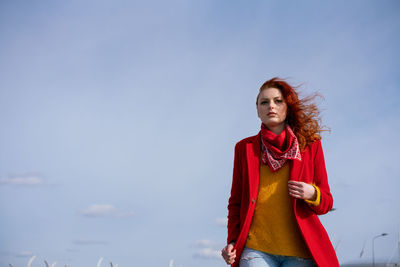 Portrait of smiling young woman standing against sky