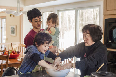 Father carrying daughter while standing by family preparing food at home