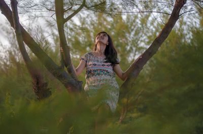 Young woman standing against trees