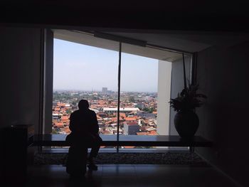 Rear view of man looking through window