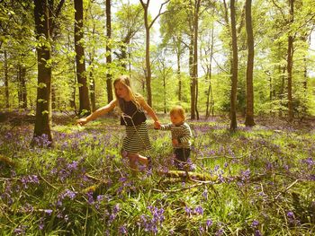 Rear view of mother with daughter standing by trees in forest