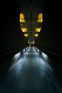 Illuminated tunnel amidst buildings at night