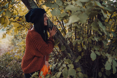 Portrait of young woman standing against plants