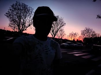 Silhouette man by car against sky during sunset