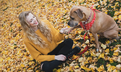 Woman with dog in autumn leaves