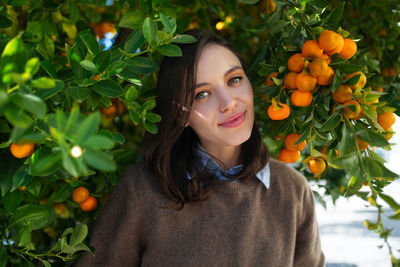 Portrait of young woman standing by flowering plant