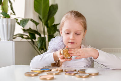 A girl student sits at a desk in the classroom and collects figures / puzzles / small toys 