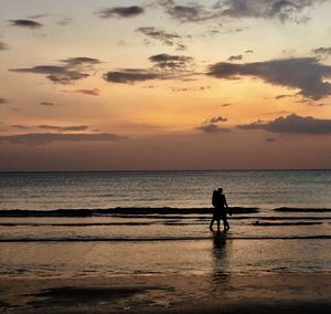 Silhouette man standing on beach against sky during sunset