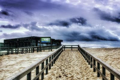 Built structure on beach against storm clouds