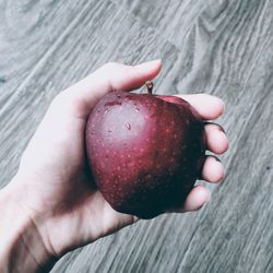 Cropped hand holding apple over table