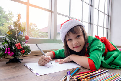 Portrait of girl drawing on paper at home