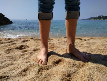 Low section of man standing on beach