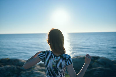 Rear view of woman looking at sea against clear sky