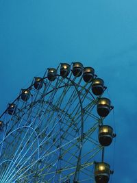 Low angle view of illuminated ferris wheel against blue sky