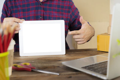 Midsection of man using laptop on table