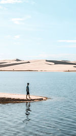 Rear view of woman walking on beach against sky