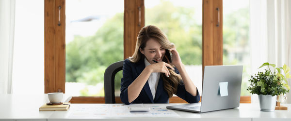 Young woman using mobile phone while sitting on table