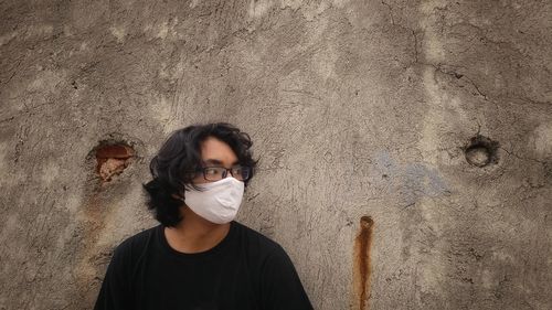 Portrait of young man standing against wall